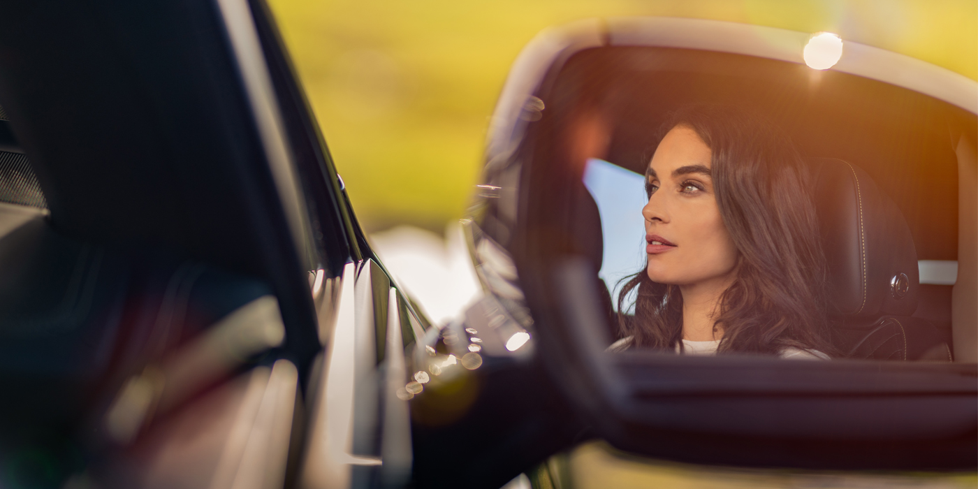 Bentley Athens profile of dark haired woman's face in mirror of Bentley car in sunlight