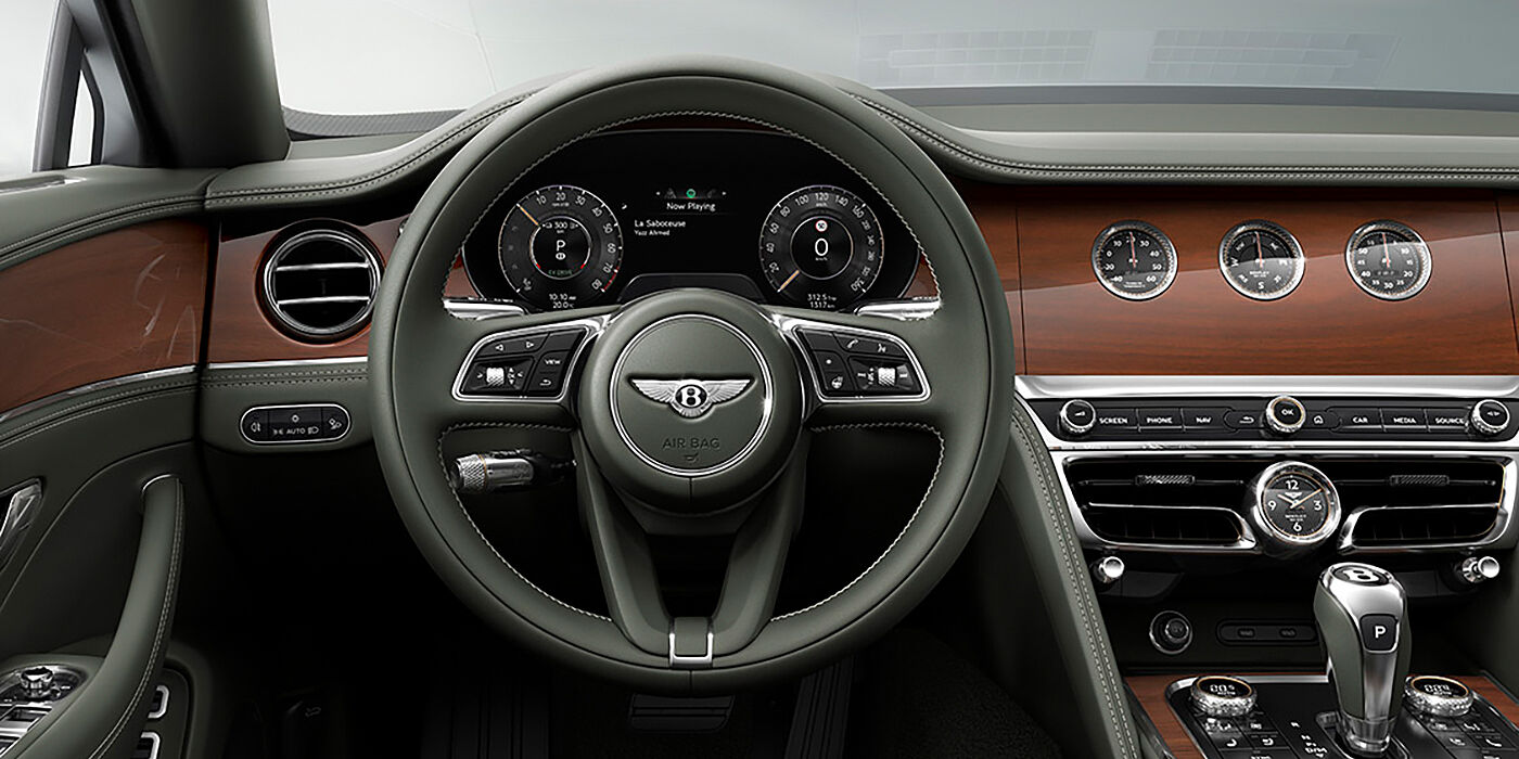 Bentley Athens New Bentley Flying Spur sedan front cabin in Cumbrian Green hide and Crown Cut walnut veneer showing steering wheel and Rotating Display with three clocks on face